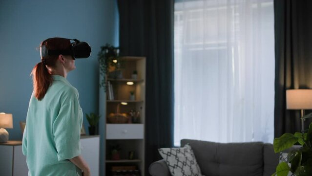 young woman uses modern technology and communicates with virtual friends wearing vair glasses while standing in room