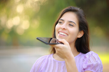 Happy woman dictating message on phone