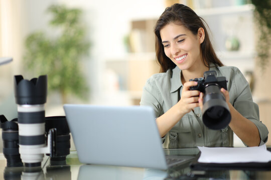 Happy photographer checking work on laptop at home