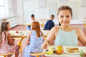 Girl holding tray with healthy food in school cafe