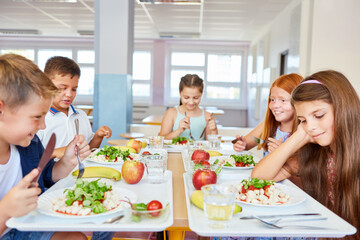 Happy students eating food during lunch time in school cafe