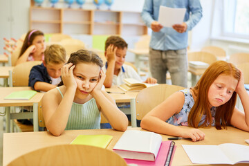 Tired students sitting on bench in classroom