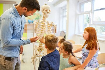 Teacher explaining human skeleton to students in classroom
