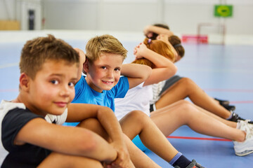 Schoolboy doing exercise with friends during gym class