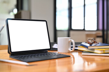 Digital tablet, coffee cup, books and glasses on wooden office desk
