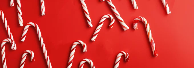 Foto op Canvas Banner Christmas background with Xmas candy canes. Top view, flat lay. Christmas candy cane on red background. Copy space for text. © annebel146