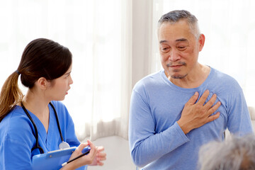 Obraz premium The caregiver therapist sits with a group of Asian senior people in a circle for checking physical and mental health in a group elderly therapy session. The nursing home facilitates a support group
