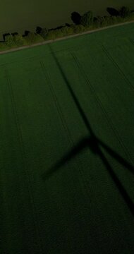 Shadow of a wind turbine wind mill on a green field in sunny weather