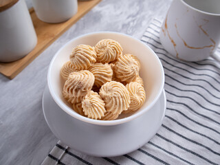 Sago Cookies are neatly presented in a white bowl with an attractive arrangement. They are isolated against a white background in a dining table setting.