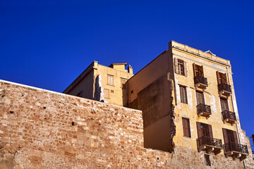 Stone wall and historic building with shutters and balconies in the town of Chania on the island of Crete, Greece