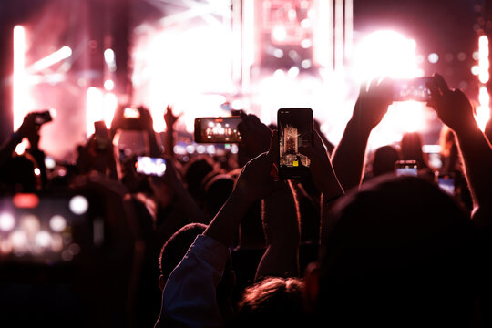 Crowd at a music festival. They are recording the show with their smartphones camera.