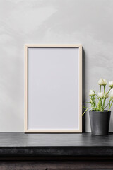 Fototapeta na wymiar Blank vertical picture frame mockup hanging on a plain wall with wooden desk table and flower vase
