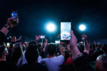 Crowd at a music festival. They are recording the show with their smartphones camera.