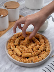 Kue Kastengel or Kaastangels are neatly presented on a white plate with attractive decorations. They are isolated against a kitchen background.