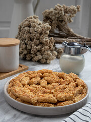 Kue Kastengel or Kaastangels are neatly presented on a white plate with attractive decorations. They are isolated against a kitchen background.