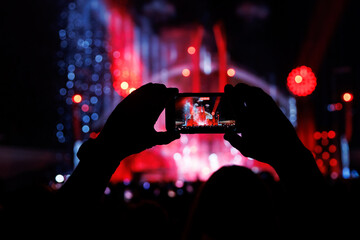 Silhouette of a hand with a mobile phone camera and enjoying the concert