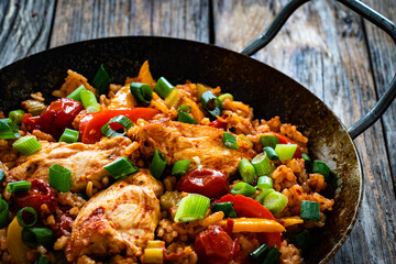 Jambalaya one pot dish - fried chicken breasts with white rice, tomatoes, bell pepper and celery on wooden table
