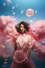 Beautiful young woman in pink dress with soap bubbles on blue background