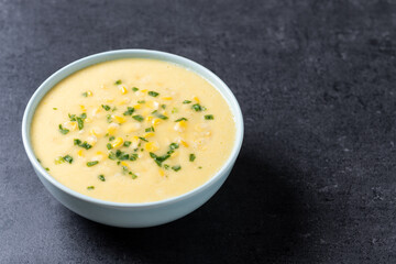 Corn soup in green bowl on black background. Copy space