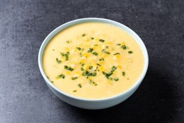 Corn soup in green bowl on black background
