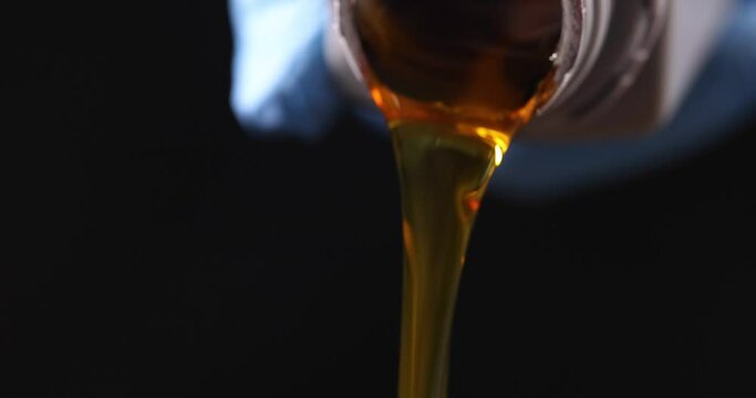 Clear yellow oil is poured from plastic bottle. Car engine oil drop pouring from bottle into car wash