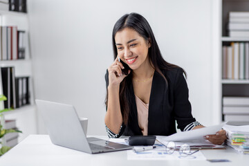 Cheerful business Asian woman office making telephone call share good news about project working in office workplace, business finance documents concept.	