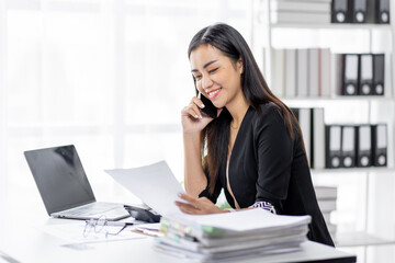 Cheerful business Asian woman office making telephone call share good news about project working in office workplace, business finance documents concept.	