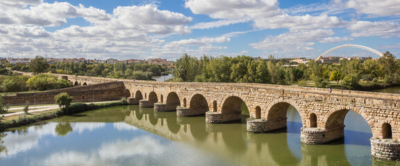 Panorama of the historic roman bridge reflecting in the Guadiana river in Merida, Spain - obrazy, fototapety, plakaty