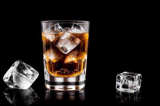 Whiskey or bourbon in a rocks glass with a big ice cube, shot with hard  light and harsh shadows, pink tile backdrop, copy space Stock Photo