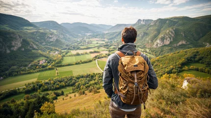 Gartenposter Man on top of a cliff, hiker with a hiking backpack looking at a beautiful landscape, vegetation and mountains © OpticalDesign