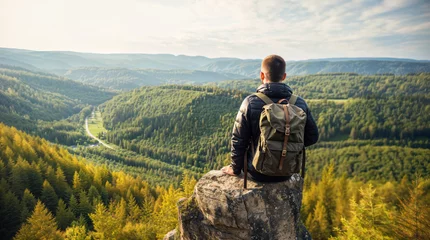 Keuken spatwand met foto Man sitting on a rock, hiker with a hiking backpack looking at a beautiful landscape, vegetation and mountains © OpticalDesign