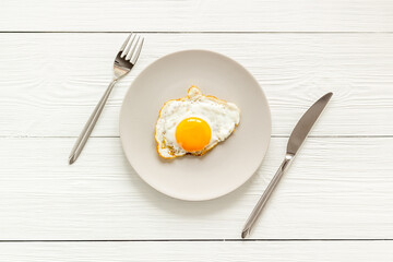 Fast breakfast with one fried egg on plate, top view