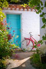 Vieux vélo rouge à côté d'une vieille porte bleu dans une rue fleuries en France.