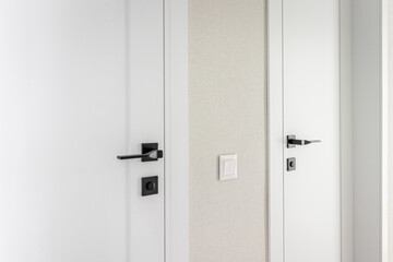 Modern black door handle on white wooden door in interior. Knob close-up elements