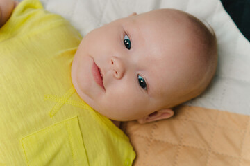 Portrait of a newborn baby in a yellow bodysuit.
