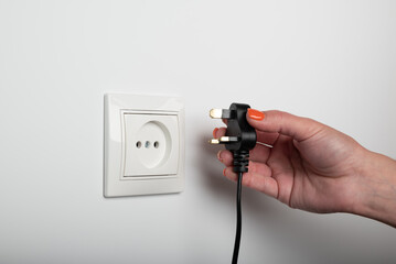 Different standards for electrical outlets. Unsuitable connector and plug in the hand of a person....