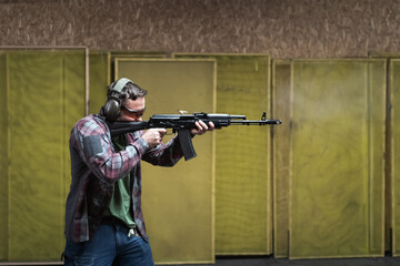 A guy shoots from an AK 74m at a shooting range.