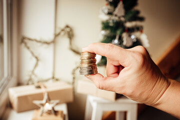 Concept of Christmas budget and finances. Woman hand holding money against Christmas tree and...