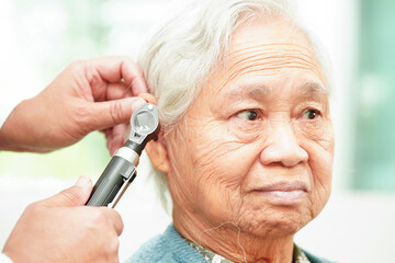 Otolaryngologist or ENT physician doctor examining senior patient ear with otoscope, hearing loss problem. .