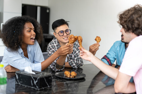 Group of young friends eating fast food at home. Multiethnic group of people having lunch together. Communication concept