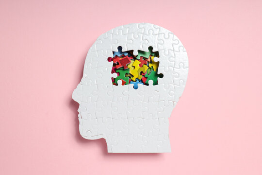 Puzzle head on pink background, top view
