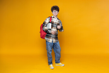 Fototapeta premium Curly teenager with a briefcase, on a yellow background.