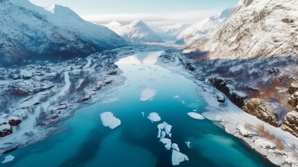 Obraz premium Mountain river on a beautiful sunny day. Snowy winter landscape of mountains with a cold clear river. Global Warming and melting ice concept. Beautiful drone shot of the river in the mountains.