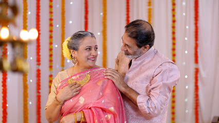 A charming old man giving a Diwali gift to his beautiful wife - putting necklace  old age love  celebrating golden jubilee  happy anniversary  gold necklace. Old couple celebrating Diwali festival ...