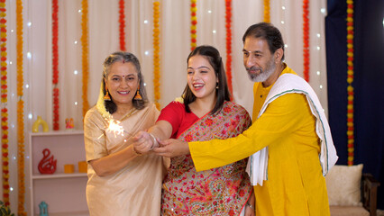 South-Indian family enjoying the festival of Diwali - festival celebration  crackers  family union  family gathering  nuclear family. A loving family celebrating Deepawali and cracking the crackers...