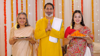 A loving South-Indian family greets guests at their house entrance - posing for the camera  Diwali festival. Beautiful young woman with family - nuclear family  traditional clothes  Diwali festival...