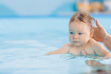 Fototapeta na wymiar Teaching dive underwater happy baby girl in swimming pool, lesson for small swimmer