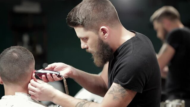 Barber cutting bearded brutal man, reflection in the mirror