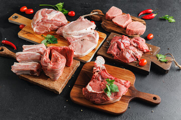 Variety of raw beef meat and pork ribs, pig steaks for grilling with seasoning on wooden board,...