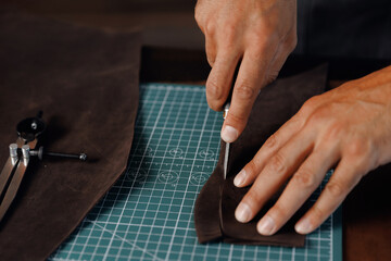 Closeup Hand of Tailor, cobbler use natural brown leather, shoemaker working with skin textile in workshop